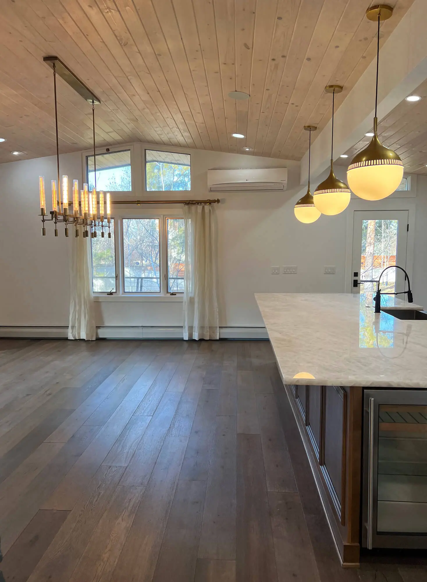 Modern kitchen and living area featuring a vaulted wood-paneled ceiling, pendant lighting, and professional interior painting services by Accent Painting.