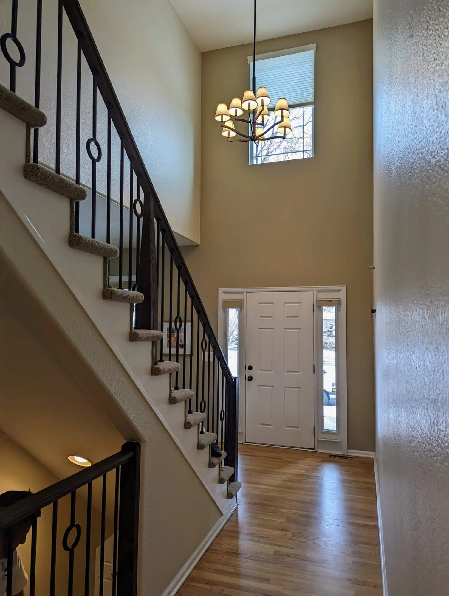 Modern interior entryway featuring a grand vaulted ceiling, custom light fixture, and elegant hardwood flooring, expertly finished by Accent Painting.