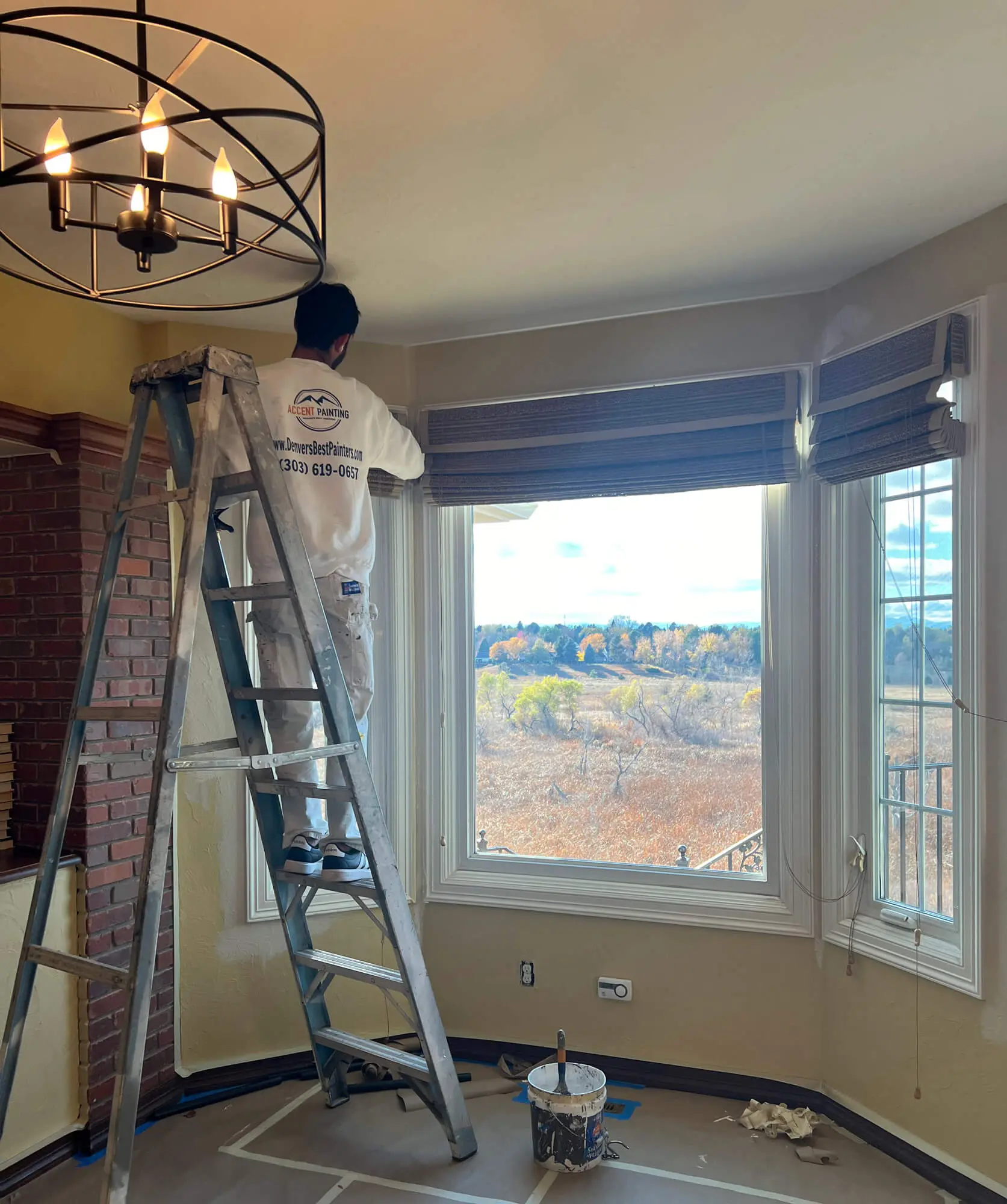 Professional painter from Accent Painting using a ladder to perform interior painting services in a residential home in Denver, CO.