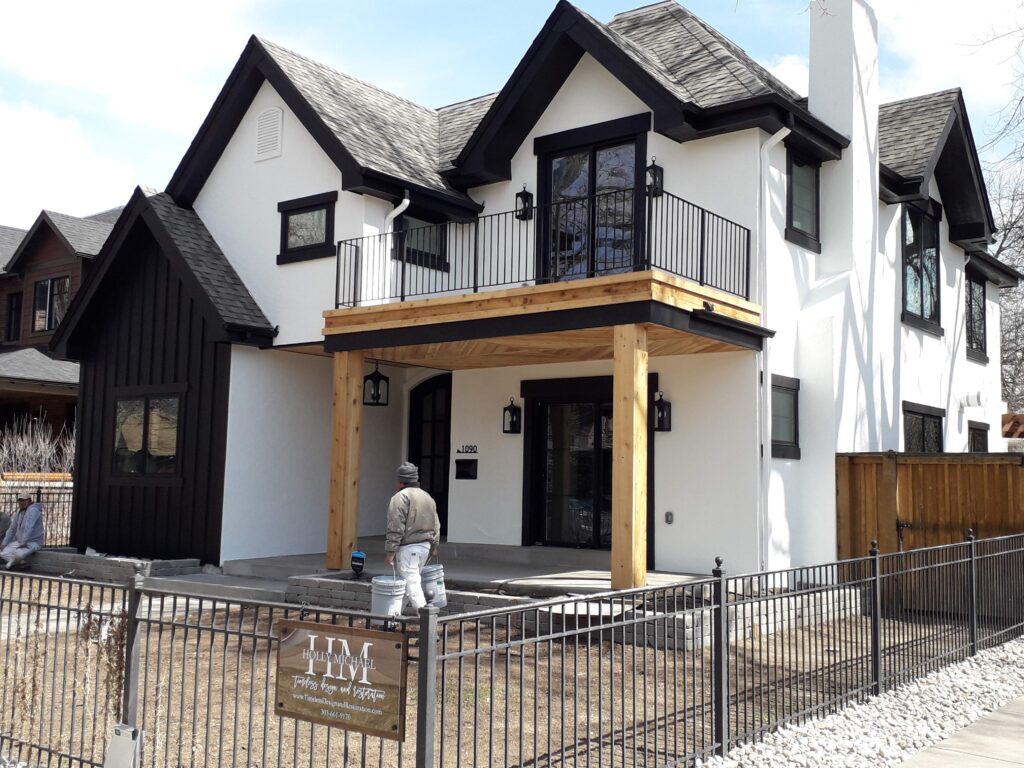 Exterior corner view of new construction home with white exterior stucco and black trim