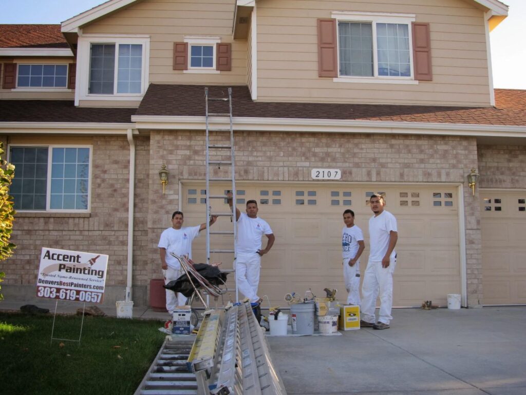 Closeup of painting crew and ladder in front of beige house