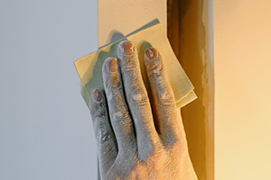 Closeup of person sanding drywall