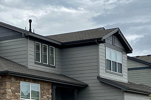 Roofline of home with grey painted siding and dark roof