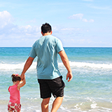 Man walking on beach with daughter