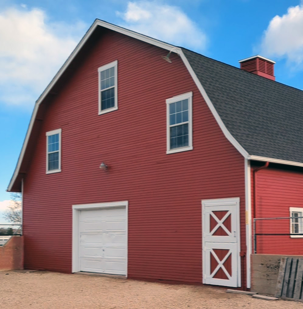 Exterior of gambrel roof barn painted red with white trim from Benjamin Moore paints