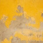 Close-up image of exterior wall paint severely peeling and deteriorating, illustrating the impact of Denver's harsh weather elements